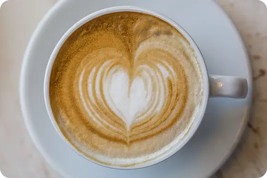 Kafijas tase ar latte art sirds zīmējumu putās