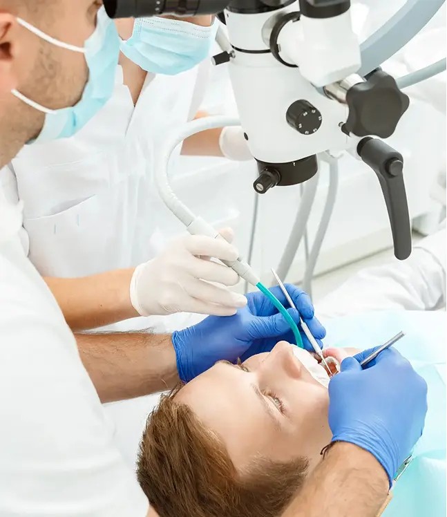 Zobārsts veic saknes kanāla ārstēšanu pacientam, izmantojot dentālo mikroskopu