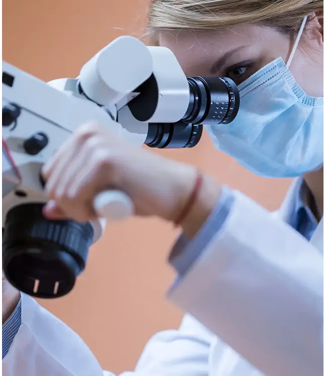 Zobārsts ar masku strādā ar dentālo mikroskopu saknes kanāla ārstēšanai