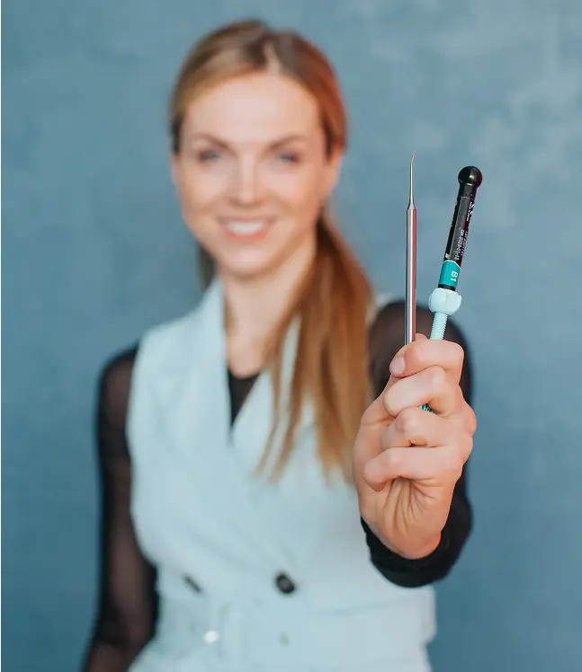 Smaidīga zobārste tur zobārstniecības instrumentus