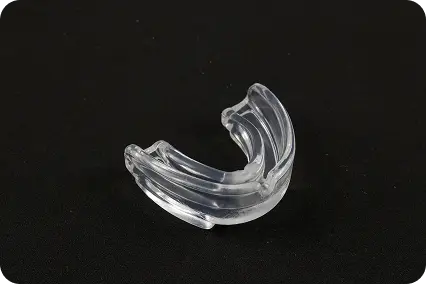 Zobu nakts kape bruksisma gadījumā, caurspīdīgs mutes aizsargs uz melna fona